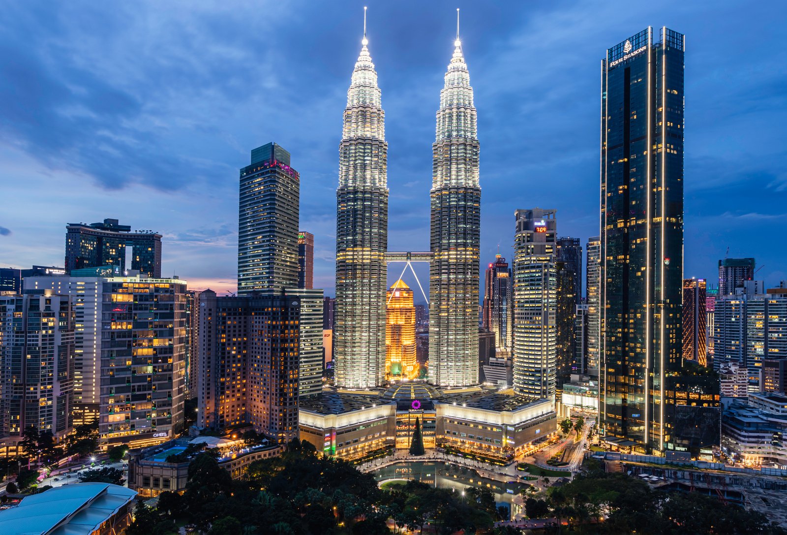 Petronas Twin Towers in Kuala Lumpur illuminated at blue hour, surrounded by the KLCC skyline